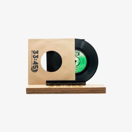 Partial view of a black vinyl record in a kraft paper sleeve with a circular hole, mounted on a wooden display stand.