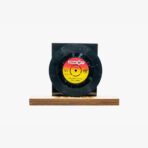 2301450027C | 3345 Records Vinyl record mounted on a wooden base with a black sleeve behind it, label visible in red-yellow center.