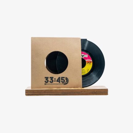 Vinyl record partially inserted in a brown cardboard sleeve with a circular window, placed on a wooden display base.
