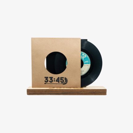 Black vinyl record partially visible from a kraft cardboard sleeve with a circular window, resting on a wooden base; '33:45' text on the sleeve.
