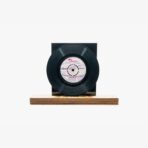 2301450032A | 3345 Records Black vinyl record mounted on a dark display with a wooden base on a white background.