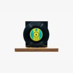 2301450037B | 3345 Records Black vinyl record mounted on a wooden platform with a blue‑yellow label, against a white background for display purposes.