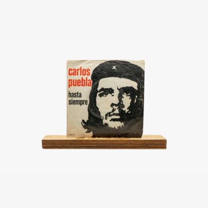 2301450039A | 3345 Records Stencil-style poster of Che Guevara's face with red text 'carlos pueblo hasta siempre' on beige paper, resting on a wooden base.