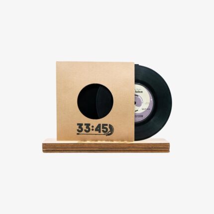 Black vinyl record partially pulled from a brown cardboard sleeve with a circular window, resting on a wooden base (reads 33:45).