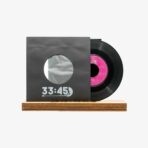 2301450079A | 3345 Records Vinyl record partially pulled from a dark sleeve labeled 33:45, resting on a wooden base against a light background.