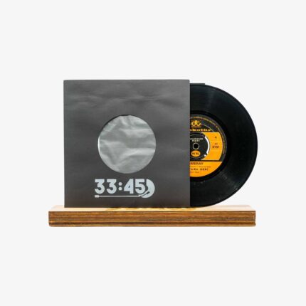 Vinyl record partially slid from a gray sleeve with a circular window, displaying a wooden stand below.