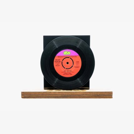 Vinyl record mounted on a black square stand atop a wooden base against a white background, showing an orange label at the center.